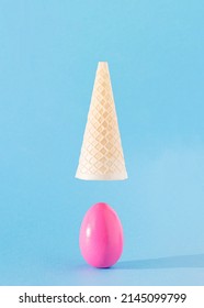 Egg Pink Dropped Out Of Ice Cream Cone Flying Above. Easter Aesthetic Food Design Concept Idea. Holiday Spring Sunny Moment