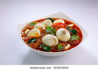 Egg roast or Indian egg masala curry,spicy red egg roast arranged in a white ceramic bowl and garnished with curry leaves,coriander leaf,garlic cloves and fresh red chilli on white colour background. - Powered by Shutterstock