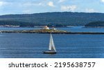 Egg Rock Light - A telephoto shot of a small sailboat passing in front of Egg Rock Light Station at entrance of Frenchman Bay on a sunny Autumn morning, as seen from Mount Desert Island. Maine, USA.