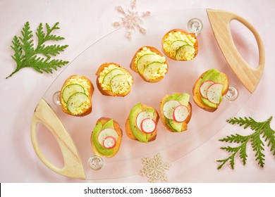 Egg Salad With Cucumber And Avocado Slices With Radish On Crusty Toasts On Glass Serving Tray.  Pink Background With Festive Accents From Overhead.