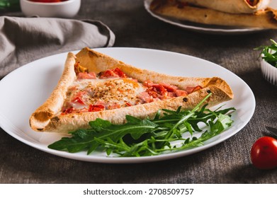 Egg, sausage and tomatoes baked in a triangular tortilla on a plate on the table