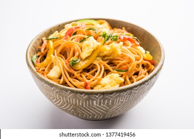 Egg Schezwan/hakka noodles, popular indochinese food served in a bowl with chopsticks. selective focus