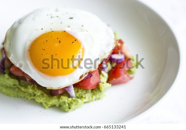 egg sunny side up on a bed of
guacamole 
egg sunny side up on tomato tartar with
avocado