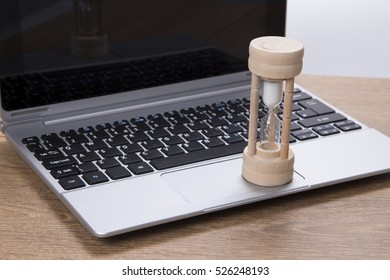 Egg Timer On A Business Laptop With Sand Running Through The Bulbs Measuring Passing Time To A Deadline Conceptual Of Urgency