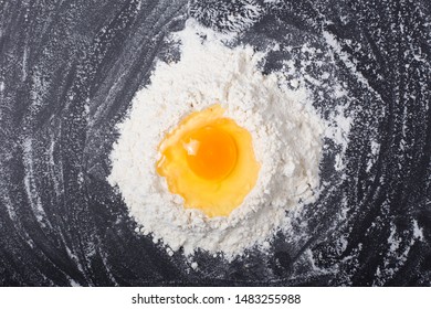 Egg Yolk Spilled Into Flour On Black Background