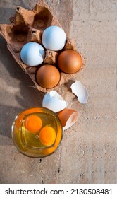 Egg Yolk And Egg White In Glass, By The Yellow And White Eggs In Carton Box. Above Flat Close Up View. Vertical Image