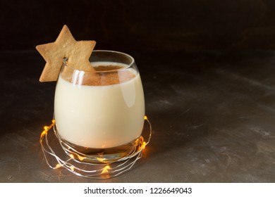 Eggnog cocktail and star cookies on black background.