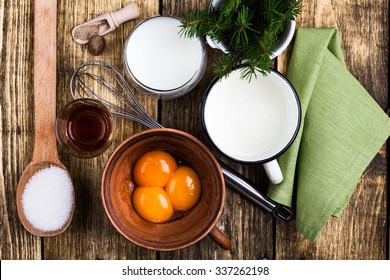 Eggnog  Ingredients On Rustic Wooden Table Viewed From Above.  Egg Milk Punch With Raw Egg Yolks, Milk, Cream, Sugar,  Bourbon, Ground Nutmeg