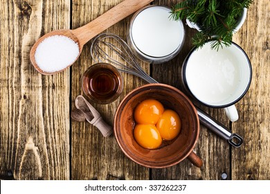 Eggnog  Ingredients On Rustic Wooden Table Viewed From Above.  Egg Milk Punch With Raw Egg Yolks, Milk, Cream, Sugar,  Bourbon, Ground Nutmeg