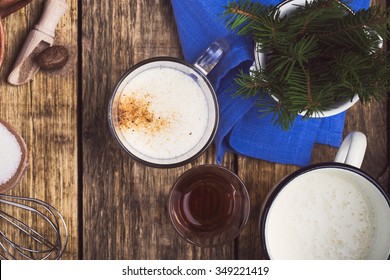 Eggnog  Ingredients On Rustic Wooden Table Viewed From Above.  Egg Milk Punch With Raw Egg Yolks, Milk, Cream, Sugar,  Bourbon, Ground Nutmeg