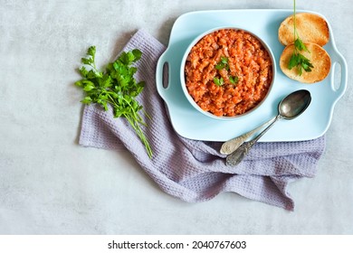 Eggplant caviar in blue bowl and fresh vegetables on background. Flat lay, top view, copy space