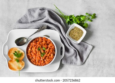 Eggplant caviar in a bowl and fresh vegetables on background. Flat lay, top view