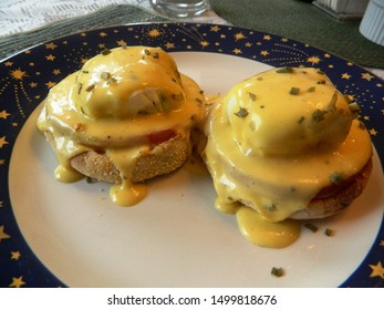 
		Eggs Benedict on a white plate with a blue border and yellow stars			