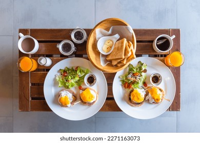 Eggs Benedict with salad, bread, tea, orange juice.
Eggs Benedict toasted English, ham, poached eggs and buttery hollandaise sauce
Top view of Egg benedict in white plate on wooden table for breakfast