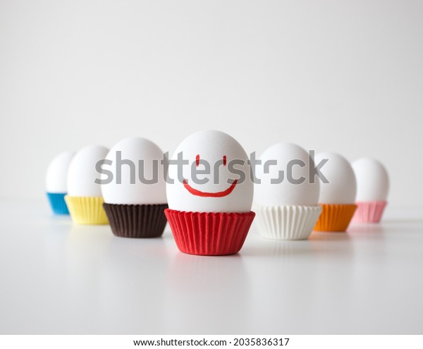 Eggs positioned in a triangle position on white\
background, positive concept idea with smiley face for egg\'s day,\
selective focus effect