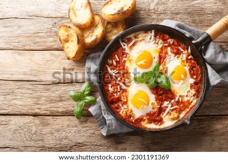 Eggs in Purgatory is a delicious Southern Italian dish consisting of fried eggs in a spicy tomato sauce with onions and garlic closeup on the skillet on the table. Horizontal top view from above
