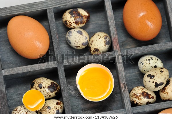 Eggs\
quail and chicken in a box, divided into sections. The box is dark.\
Some eggs are broken. Close-up. Macro\
photography.