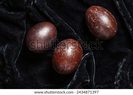 Eggs stained with wine and covered with mother-of-pearl on a dark velvet background. Easter concept.