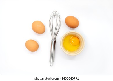 Eggs, A Whisk And One Egg Yolk On A White Background