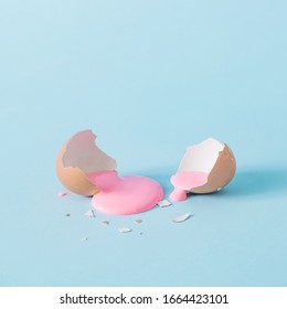 Eggshell With Pastel Pink Paint. Creative Copy Space On Blue Background. Minimal Easter Holiday Concept.