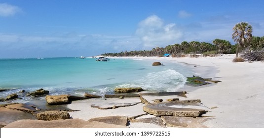 Egmont Key Island Beach With Stone And Rocks In The Beautiful Aqua Blue Ocean And On The White Sand Beach. Palm Trees And A Blue Sky With Clouds In The Background. 