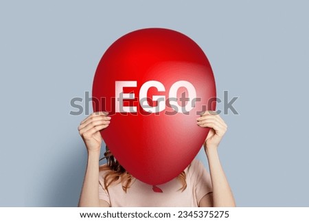 ego concept. Girl holding a balloon with the word EGO isolated on a gray background. Narcissism selfishness arrogance concept