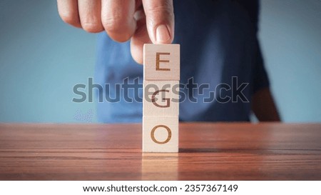 Ego on wooden alphabet blocks reading - Ego - balanced in the palm of his hand in a conceptual image