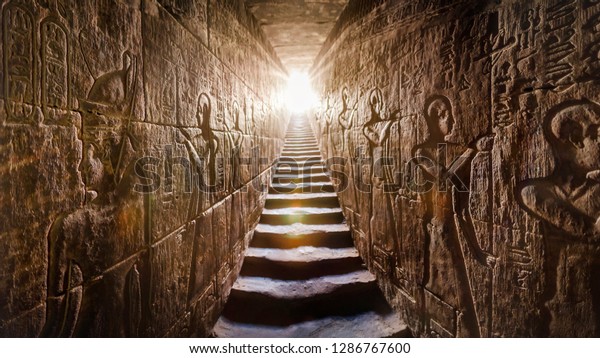 Храм АБИДОС ЕГИПЕТ Сети I, завершенный Рамзесом II (-1200). Проход, обращенный двумя светящими стенами, полными египетских иероглифов, освещенный теплой оранжевой подсветкой от двери в