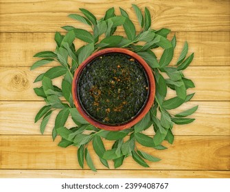 Egyptian molokhia soup in Pottery dish with molokhya leaves outside on wooden background top view