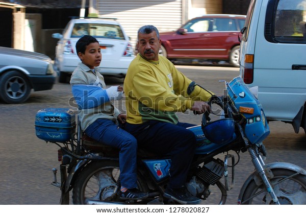 An Egyptian rides his son on\
a motorcycle. The child\'s hand is broken. They were with a doctor.\
The Arab Spring begins. Cairo, Egypt, Middle East, March 27,\
2011.