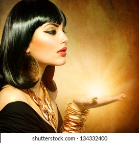 Egyptian Style Woman with Magic Light in Her Hand. Golden Jewels. Egypt Styled Makeup. Gold Light. Jewellery