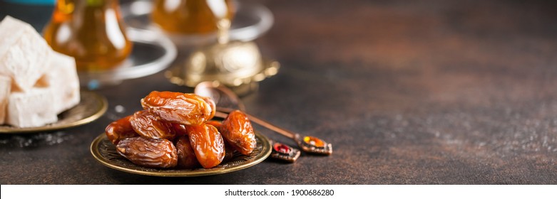 Eid mubarak with arabic coffee pot and dates. Dried dates and tea in the Arab glasses against a dark background. Ramadan, Eid concept