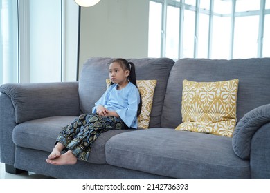 Eid Mubarak Celebration Moment, Young Malay Girl Sits On The Sofa Watching Television.