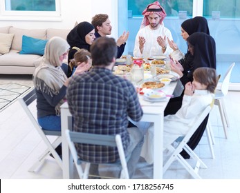 Eid Mubarak Muslim People Praying Before Iftar Dinner. Eating Traditional Food During Ramadan Feasting Month At Home. The Islamic Halal Eating And Drinking At Modern Western Islamic Family