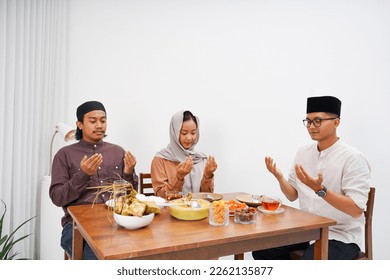 Eid Mubarak Muslim people praying before eating. Eating traditional food during Ramadan feasting month at home. The Islamic Halal Eating and Drinking at modern asian Islamic family