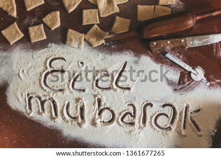 Eid Mubarak phrase written on flour. Preparation process of traditional arabic muslim cooks