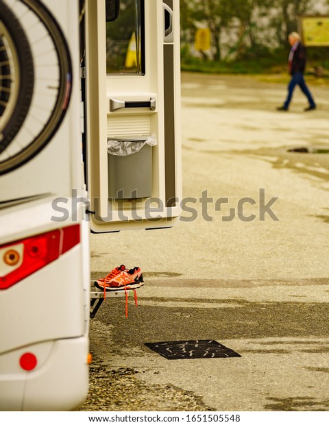 EIDFJORDEN, NORWAY- 25\
JUNE 2018: ASICS running shoes at camper car. ASICS is Japanese\
company which produces footwear and sports equipment. Detail view\
open door with\
shoes.