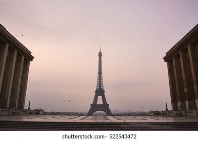 Eiffel Tower between buildings, empty square without people, early misty morning - Powered by Shutterstock