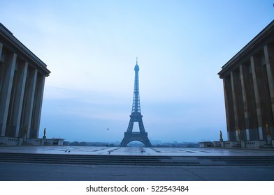 Eiffel Tower between buildings, empty square without people, early misty morning - Powered by Shutterstock