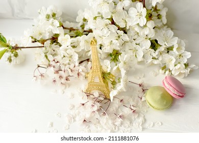 Eiffel Tower Figurine, Macarons And Branches With White Cherry Blossoms On A White Background. Spring Still Life, Travel France.