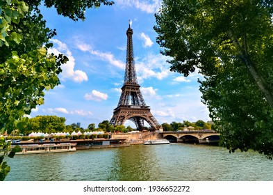 Eiffel Tower, Iconic Paris Landmark Across The River Seine With Green Leaves Vibrant Blue Sky, France