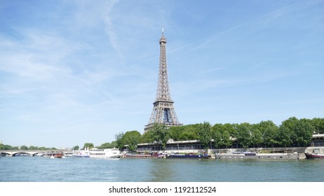 Eiffel tower and seine river with blue sky in the background and trees