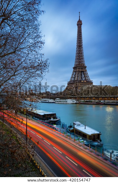 Eiffel Tower at twilight on cloudy winter morning with\
the Seine River and car light trails. Paris, Grenelle, 7th\
Arrondissement, France 