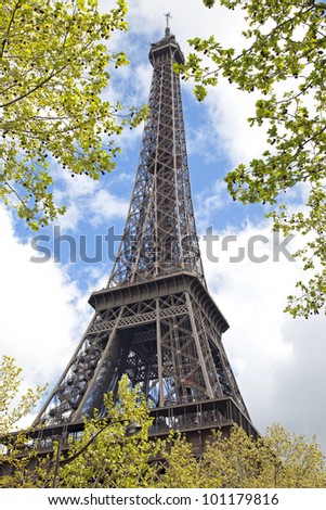 Eiffel Tower in green trees on blue sky