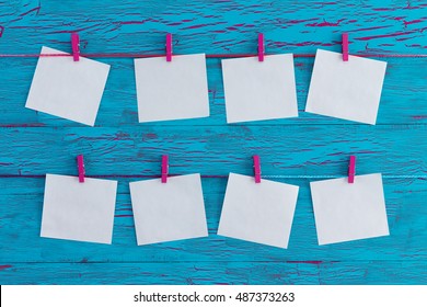 Eight Blank White Memo Pads Hanging From Colorful Wooden Pink Clothes Pegs Over An Exotic Turquoise Blue Crackle Paint Wooden Panel In A Concept Of Planning, Agenda And Organisation