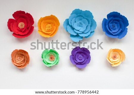 Eight handmade colorful paper flowers in rainbow colors on white background
