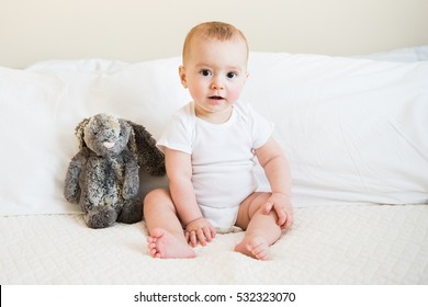 Eight Month Old Baby Boy In White Onesie Poses For Monthly Portrait