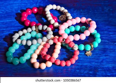 Eight multi-colored bracelets arranged in a flower shape on a blue background.
Bracelet with beads.