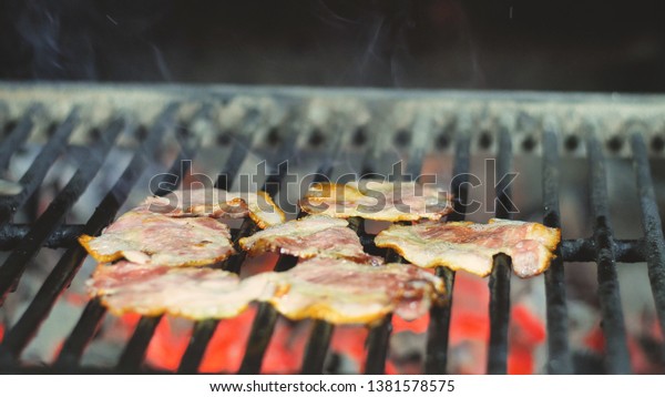 Eight slices of bacon are\
grilled in the restaurant\'s kitchen, ingredients for burgers\
salads
