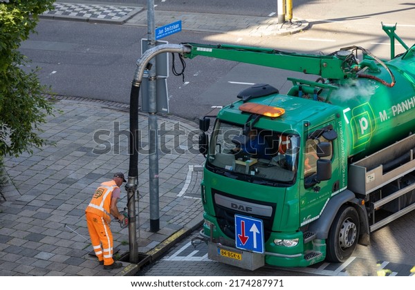 Eindhoven, July 3 2022: professional worker\
is busy with a pump car and a hose under tight pressure cleaning a\
sewer tube. Manhole and drain, part of a\
serie.